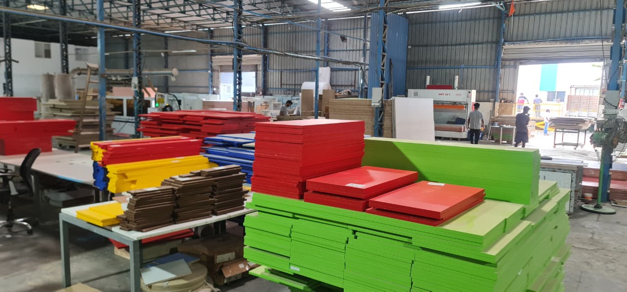 Stacks of cut and edged panels on the OutDo factory floor near Pune, with the production team at work